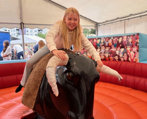 Flicka som rider på mekanisk tjur